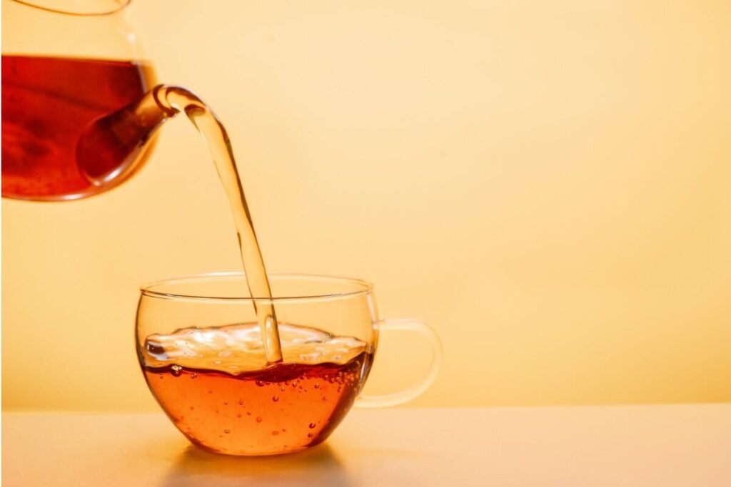 ⁠ガラスのカップに注がれる温かいあずき茶と、アンバーカラーの背景⁠