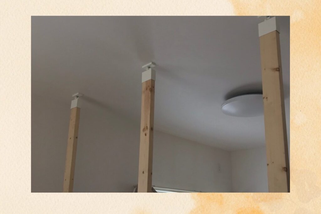 ラブリコと2x4材を使って天井と床の間に3本の柱を立てたDIYの最初のステップ画像。